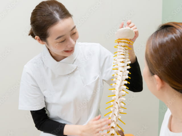 先生が患者様を横にして身体の一部を触って評価している写真